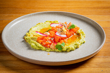 A vibrant plate of creamy guacamole topped with tomatoes, radish, and herbs, perfect to share