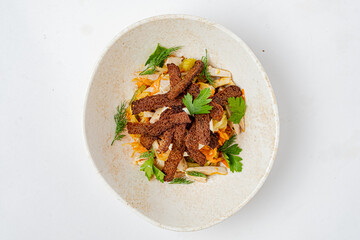 A vibrant salad with mixed vegetables, topped by crispy bread pieces and fresh green herbs