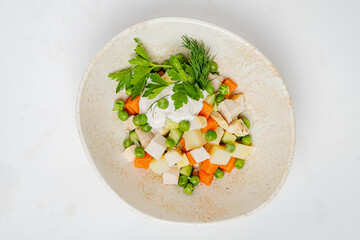 Brightly colored salad featuring diced chicken, peas, carrots, and potatoes, garnished with herbs