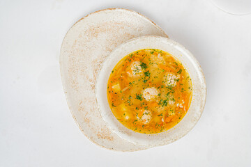 A hearty bowl of soup filled with soft meatballs and vibrant herbs, perfect for a chilly day