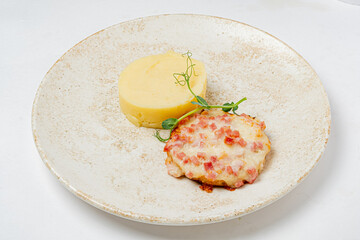 A savory patty with diced toppings paired with smooth, creamy mashed potatoes on a rustic plate
