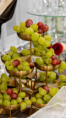Fruit arrangement on the wedding table. green and red grapes in golden bowls
