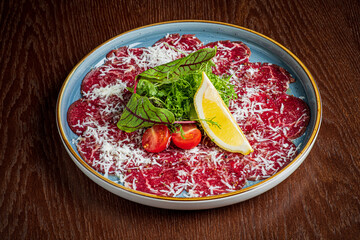 Thinly sliced meat with cheese, fresh herbs, lemon, and tomatoes