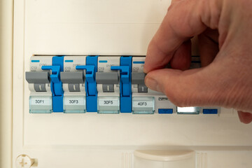 Hand is manipulating a switch inside a fuse box.