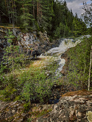 A waterfall in the autumn forest of Karelia. View of the waterfall.