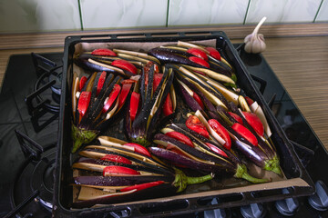 Background of sliced vegetables. Sliced eggplant and tomatoes on a platter are being prepared for baking in the oven. Fresh vegetables are sprinkled with pepper.