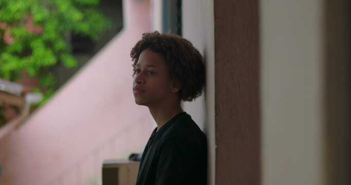 One Hispanic young boy of African descent with curly hair, deep in thought, reflecting outdoors, peaceful expression, looking upwards, moment of introspection