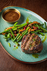 A delicious grilled steak served with fresh green beans and a rich sauce, on a stylish platter