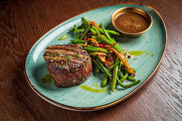 Juicy grilled steak accompanied by vibrant green beans and a rich, flavorful sauce on the side