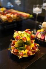 Fruit mix of grapes, pineapples and kiwi on a stand near the buffet.
