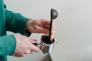 Cozy morning with mans hands tamping ground coffee in portafilter for home espresso preparation