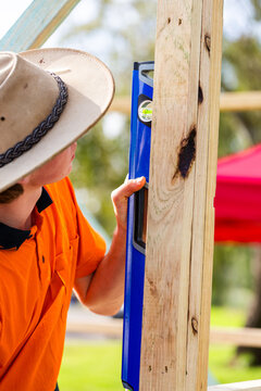 Teenaged Australian tradie apprentice using level tool on building frame