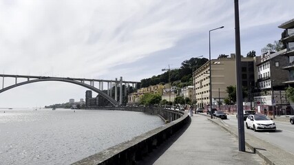 Riverside street in Porto, Portugal with view of the Arrabida Bridge, colorful residential buildings