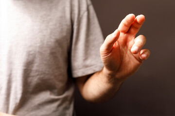 Obraz premium Man's hand gesturing upwards, suggesting direction or offering. The hand is central against a plain background. Focus on fingers and arm.