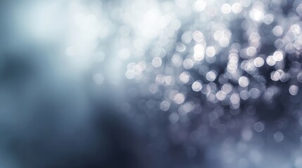 Soft-focused abstract background of frosted glass with blurred white and silver bokeh light spots creating a cool, out-of-focus shimmering texture effect across a pale blue gradient surface.