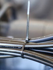 Close-up of a bundle of black electrical cables or wires neatly secured together with a black plastic zip tie in a technical or industrial setting. © Jumain