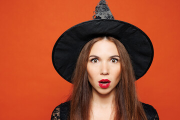 Close up young shocked surprised woman wearing black hat dress witch costume posing looking camera...