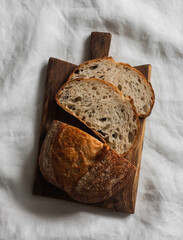 Sourdough homemade tartine bread on a wooden cutting board on a light background, top view