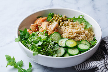 Balanced quinoa, arugula, chicken, cucumber and pea lunch bowl.
