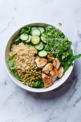Balanced quinoa, arugula, chicken, cucumber and pea lunch bowl.