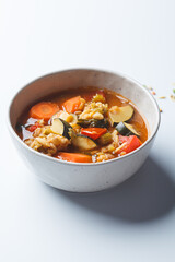 Vegetarian bean tomato soup with vegetables on white background.