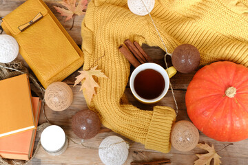 Flat lay with pumpkin, cup tea, yellow sweater, Cozy autumn composition, cinnamon sticks, books, wallet and autumn leaves, cozy fall mood, warm home atmosphere, rustic wooden background, seasonal mood