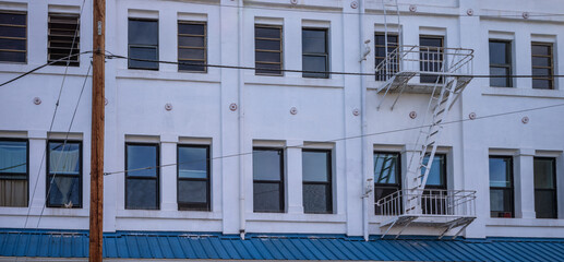 Fototapeta premium Old White Building with a Blue Awning and an Exterior Fire Escape.