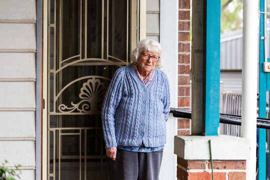 Portrait of 99 year old elderly Australian woman standing by front door of her home