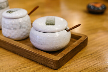 White Japanese ceramic cups with small wooden spoons placed on a wooden tray under warm natural light. Perfect for lifestyle blogs, restaurant, or interior concept visuals.