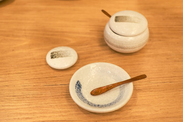 Ceramic plate with a small wooden spoon on a wooden table in warm natural light. Perfect for restaurant branding, lifestyle, or minimalist product advertisements