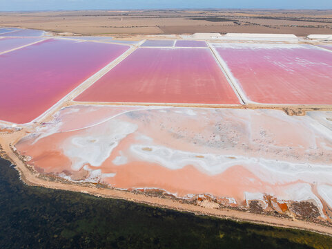 Aerial view of colourful salt evaporation ponds and levee banks at a coastal salt farm