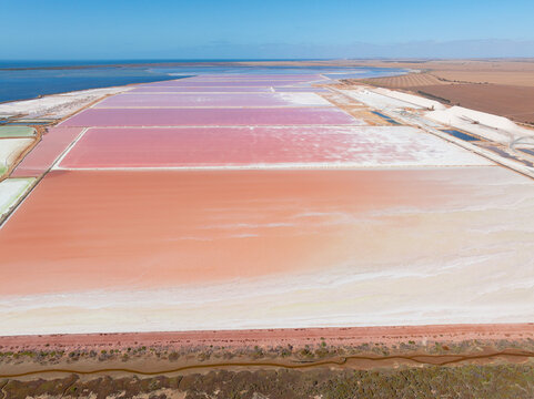 Aerial view of colourful salt evaporation ponds and levee banks at a coastal salt farm