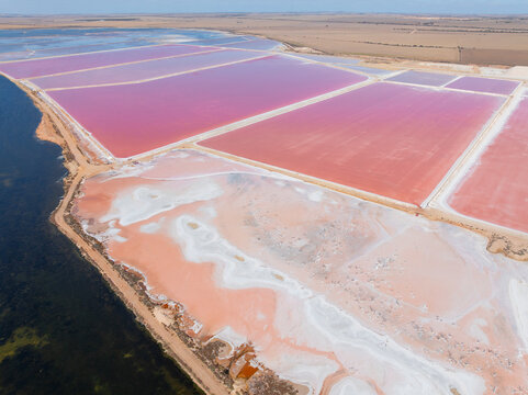 Aerial view of colourful salt evaporation ponds and levee banks at a coastal salt farm