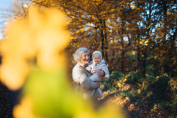 Fototapeta premium Grandma holding baby in warm embrace during fall season.