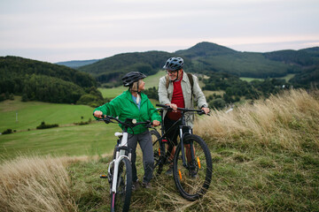 Obraz premium Older couple cycling together in nature, smiling and enjoying outdoor adventure.