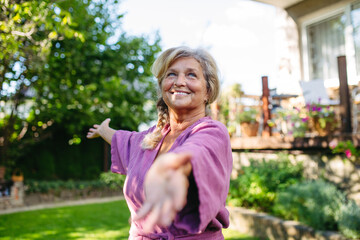 Beautiful elderly woman doing yoga in garden, morning routine.