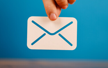 A hand holding an envelope icon against a blue background. Perfect for illustrating email,...