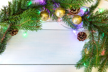 The background with spruce branches, golden balls and cones is decorated with a garland