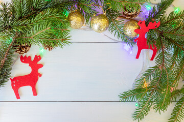 A New Year's composition with spruce branches, cones, golden balls, red figures of deer and a garland