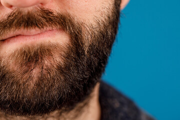 Fototapeta premium A close-up shot showcasing a handsome man's facial hair. The image highlights details, texture, and the contrast of the beard against a vibrant
