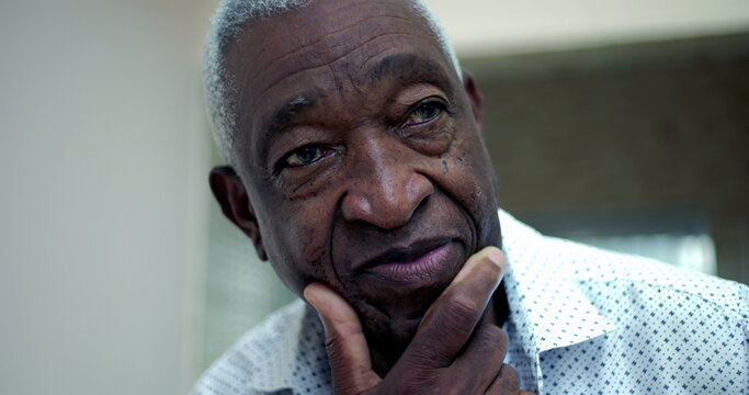 Elderly African American man resting his chin on his hand, gazing intently into the distance, reflecting thoughtfulness and contemplation in an outdoor environment