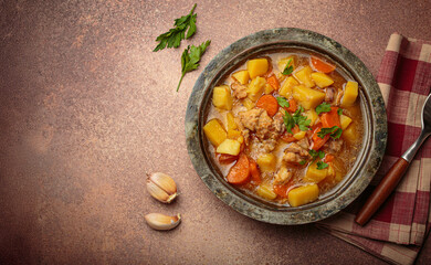 Hot chicken stew or soup with tender chicken pieces, chunky potatoes, and vibrant carrots garnished with fresh parsley in rustic bowl, comfort food for autumn and winter, copy space