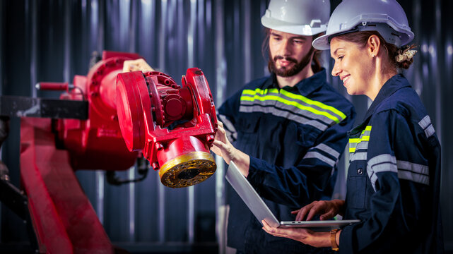 Engineer team of male and female engineers checking or maintenance electronic in AI Robot, robot arm in the manufacturing automation and robotics manufacture room.
