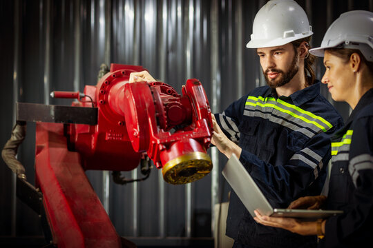 Engineer team of male and female engineers checking or maintenance electronic in AI Robot, robot arm in the manufacturing automation and robotics manufacture room.