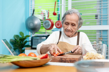 Elderly woman are cooking in their home kitchen and looking at digital tablets to learn how to cook.