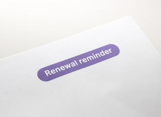 Renewal reminder notice. Snail mail letter notices sent to remind customers of a renewal of contract or subscription. Pink bubble with white text on white plain paper. Selective focus.