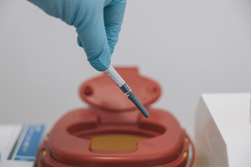 Unrecognizable doctor throws a used syringe into a special trash can