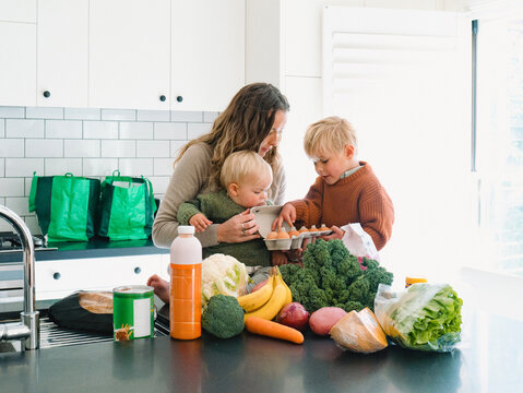 Young boy counting eggs with mum holding the baby on the countertop