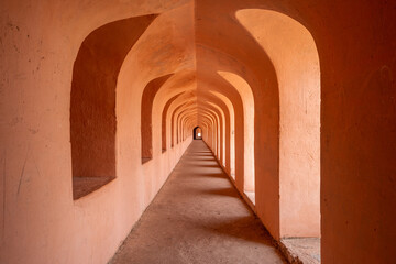 This landscape photo was taken in Asia, India, Uttar Pradesh, Lucknow, in summer. It shows the corridor of the main building of the Imambara Bara in Lucknow, under the Sun.