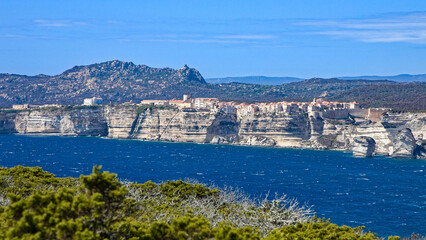 Fototapeta premium view of the medieval town of Bonifacio with its white limestone coastline and rough, deep blue turquoise sea in sunshine and blue skies